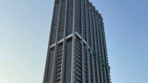 Un grand immeuble moderne, avec de nombreux balcons et une entrée imposante.