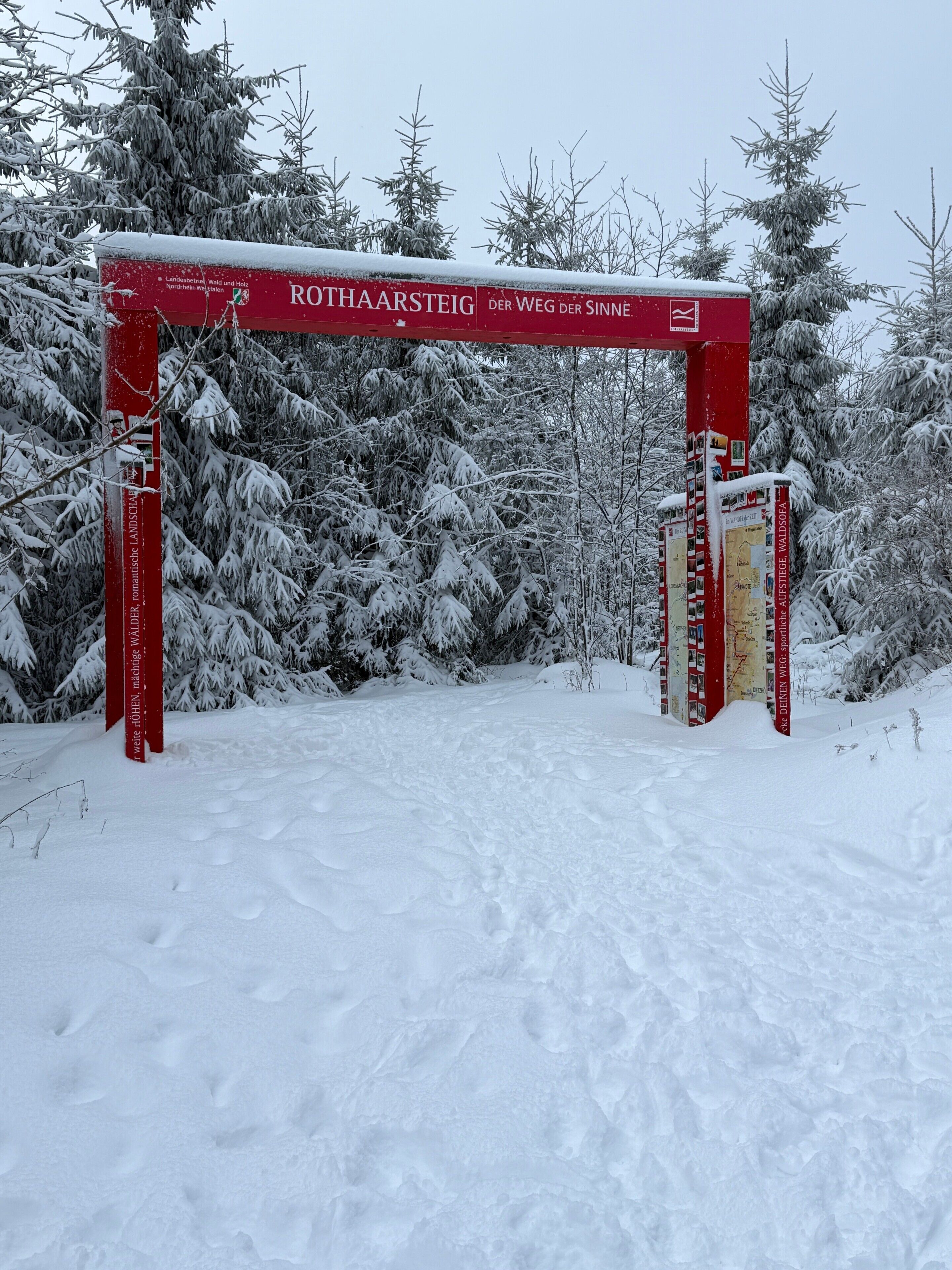 A snow-covered archway with the text 'ROTHAARSTEIG' and 'DER WEG DER SINNE.'