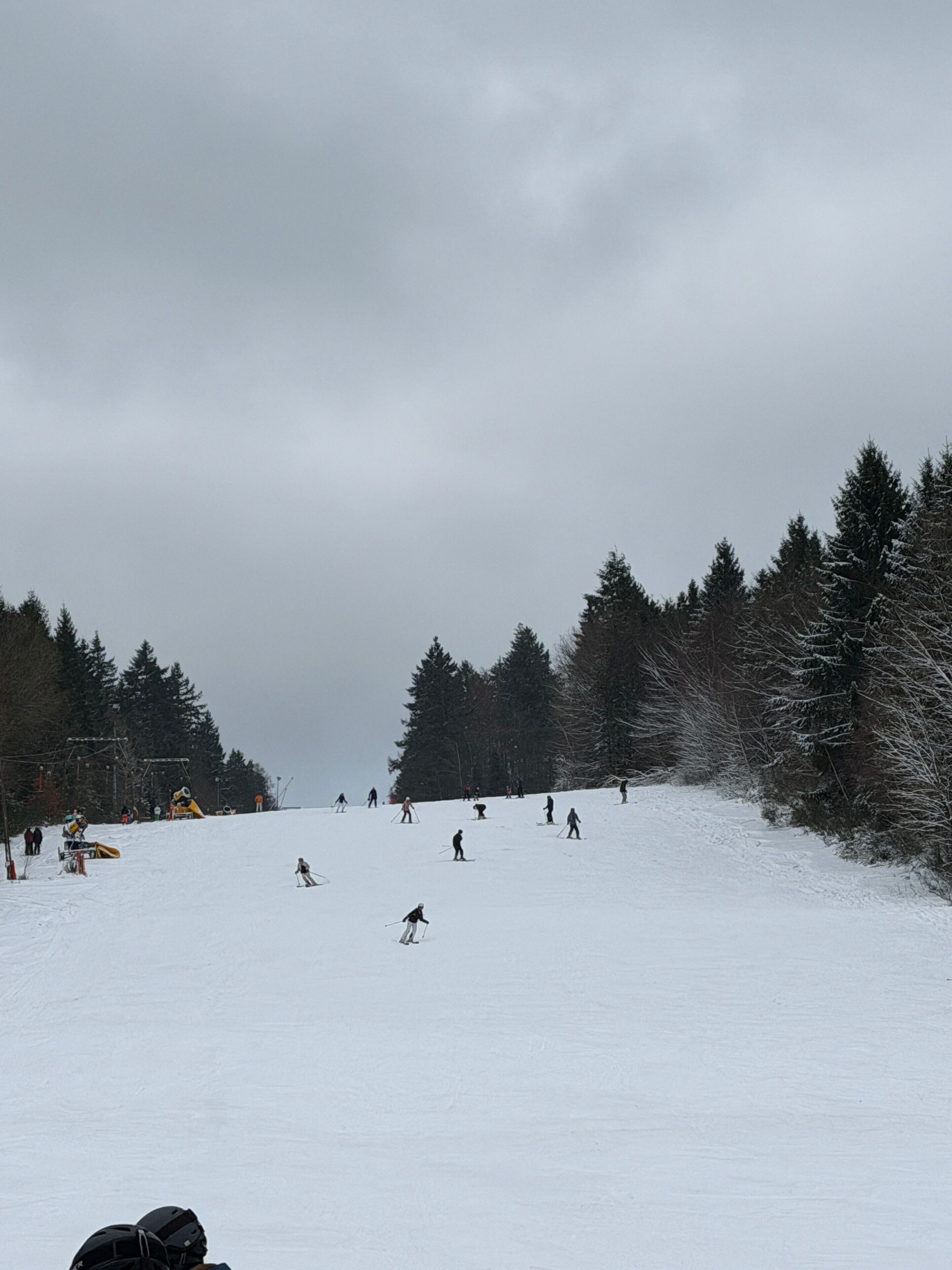 Ein verschneiter Skipisten mit Skifahrern und einer Seilbahn.
