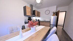 Una cocina moderna con armarios de madera, un refrigerador blanco y una zona de comedor con una mesa y sillas de madera.