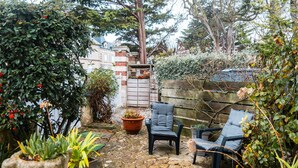 Une terrasse dallée de pierres, avec deux chaises sombres et une plante en pot.