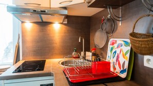 Une cuisine compacte équipée d’une cuisinière intégrée, d’un évier et d’un porte-ustensiles suspendu.