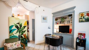 Un salon comprenant un canapé, une table à manger avec des chaises, un téléviseur et une bibliothèque.