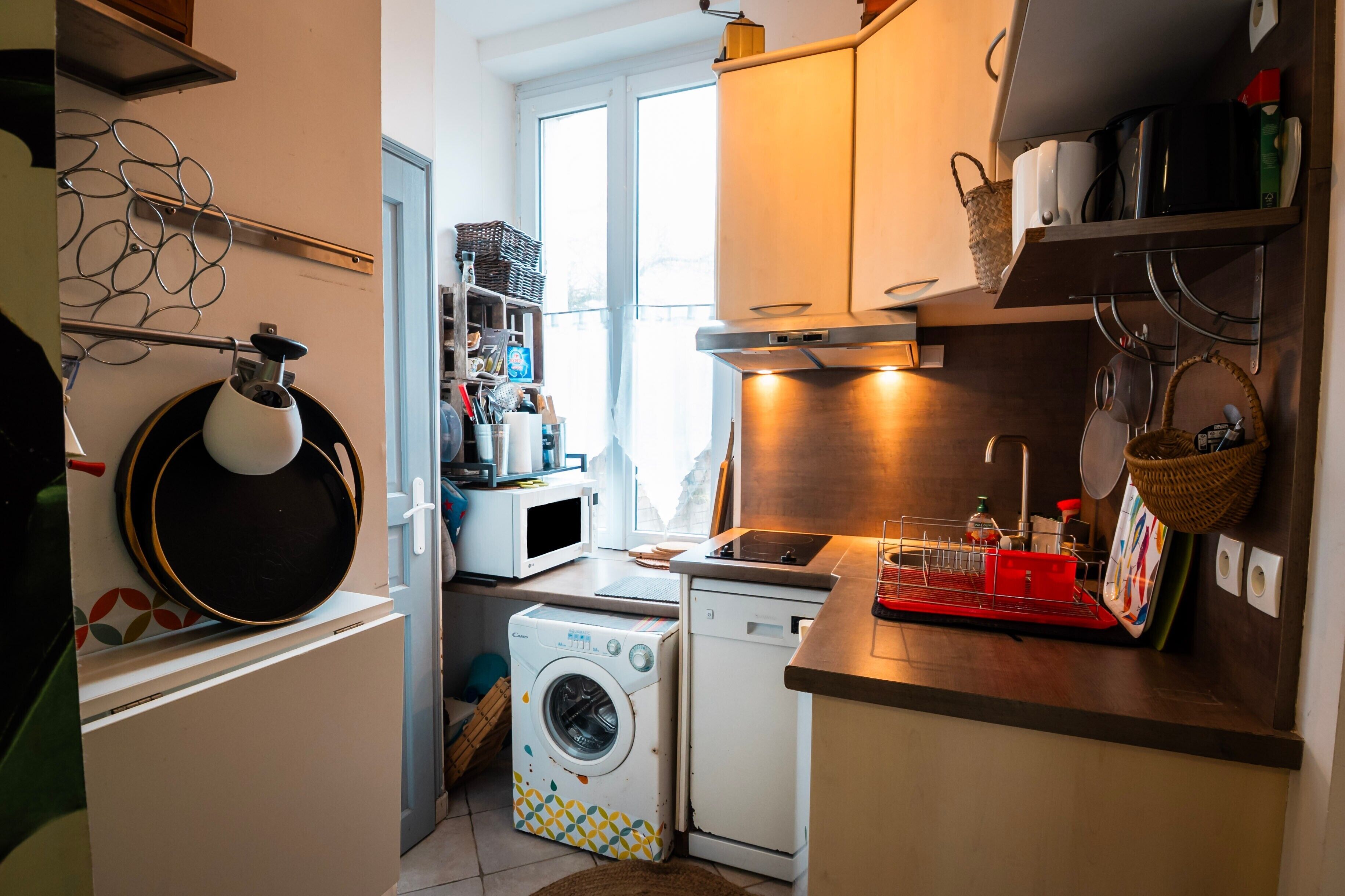 Cozinha compacta com máquina de lavar, micro-ondas e pia.