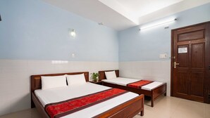 Habitación de hotel con dos camas de madera, ropa de cama blanca y un corredor decorativo rojo en la cama.