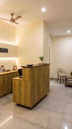 A reception desk with a wooden finish, a ceiling fan, and a digital clock.