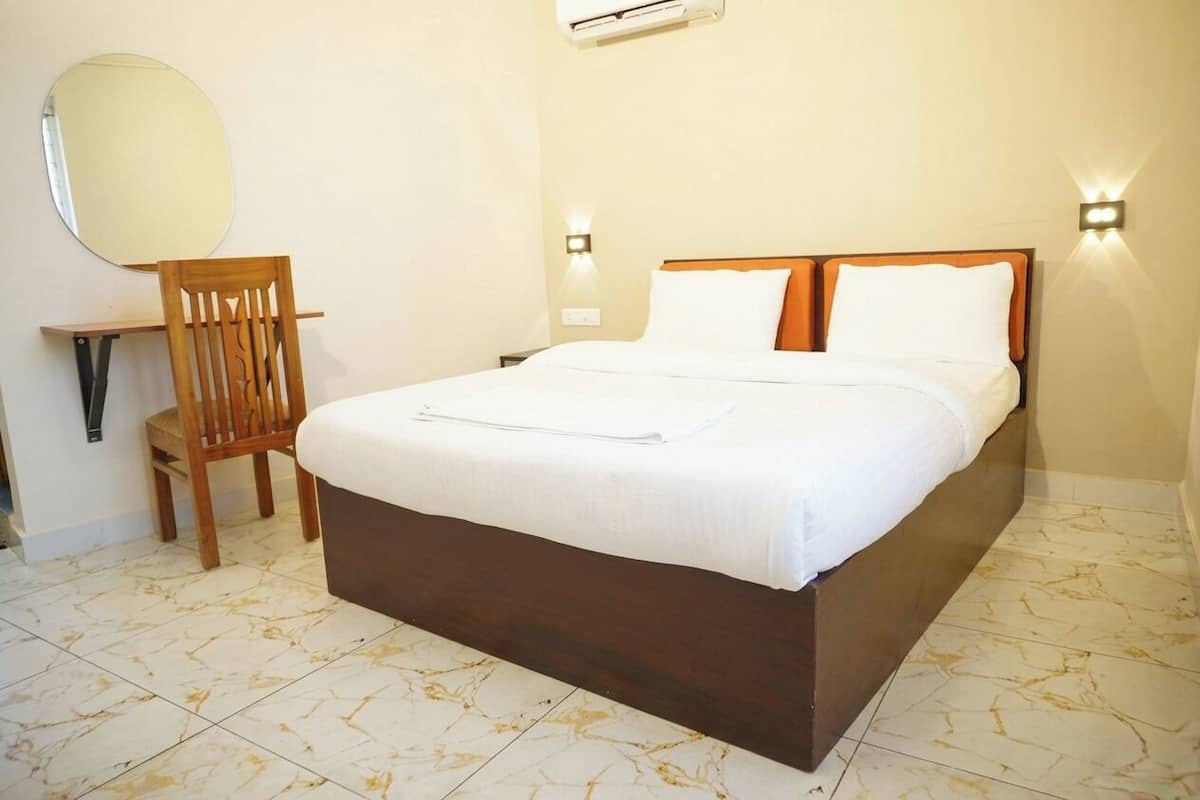 Una habitación de hotel con cama, una silla, un espejo y luces fijadas a la pared.