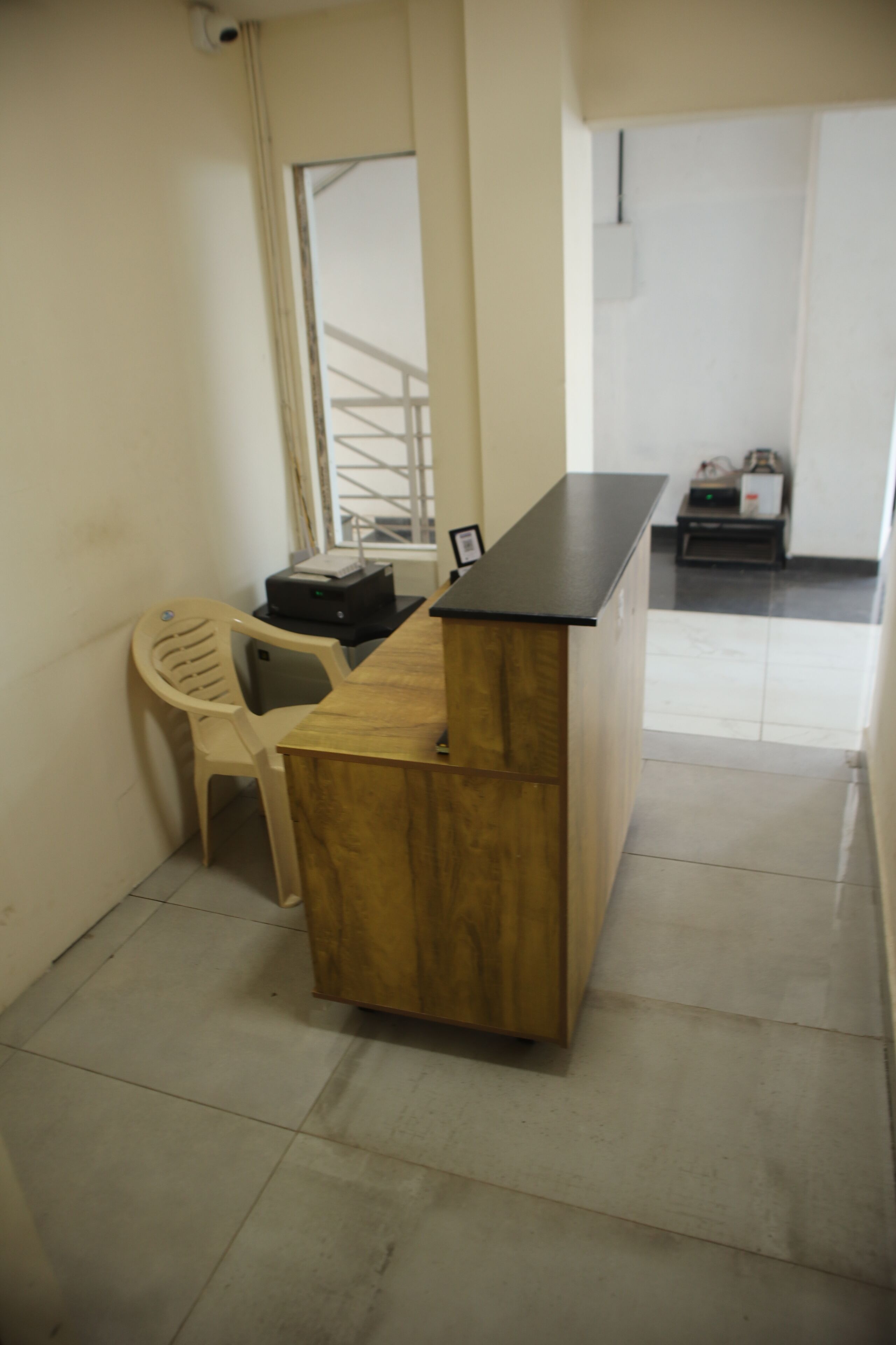 Un petit bureau avec un bureau, une chaise en plastique et une imprimante.