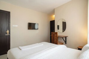 A hotel room with a bed, a desk, a chair, a television, a mirror, and a wardrobe.