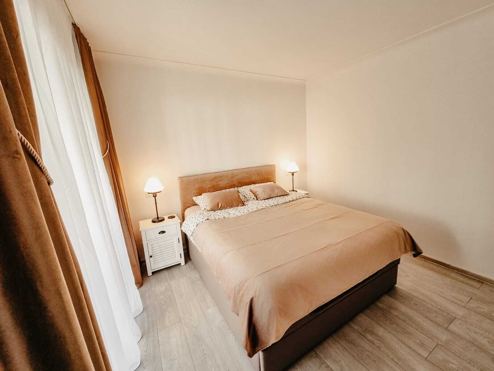 A neatly made bed with a wooden headboard, two bedside lamps, and a nightstand with a lamp.