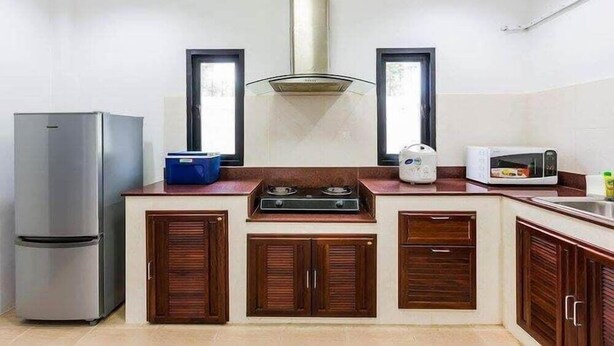 A compact kitchen with a built-in stove, a microwave, and a refrigerator. - Baan Narakorn (Krabi)