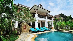 A swimming pool with lounge chairs, a covered patio, and a house with a balcony. - Baan Narakorn (Krabi)