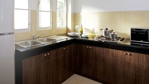 A modern kitchen with a refrigerator, double sink, wooden cabinets, and a stove. - Baan Gecko (Krabi)