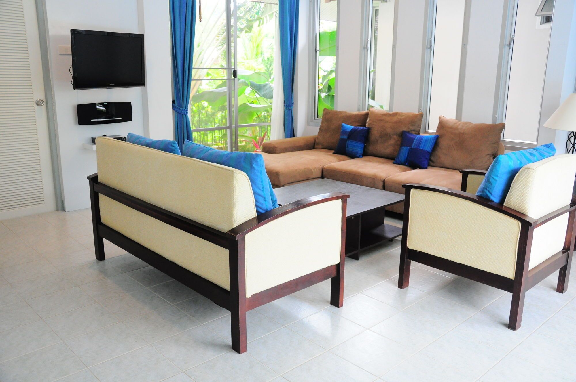 A living room with a sofa set, a coffee table, and a TV mounted on the wall.