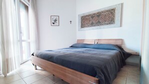 Quarto com cama de madeira, janela com cortinas, quadro na parede e design de azulejos decorativos.