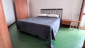Un dormitorio con una cama, un armario de madera, una mesita de noche y una silla.