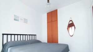 Une chambre à coucher comprenant un lit, une armoire et un miroir fixé au mur.