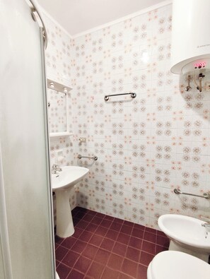A bathroom with a white sink, a mirror, and a shower with floral tiles. - Comfortable flat near the beach (Lido di Jesolo)