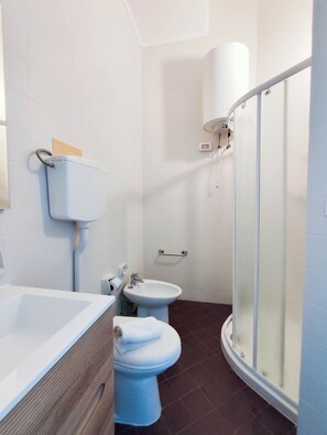 A bathroom with a bathtub, toilet, bidet, and a glass shower enclosure. - Modern apartment near the beach (Lido di Jesolo)