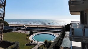 A residential building with a view of a beach and a swimming pool. - Cozy flat with balcony by the sea (Lido di Jesolo)