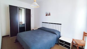 A bedroom with a bed, a wardrobe, a chair, and a bedside table. - Cozy flat with balcony by the sea (Lido di Jesolo)