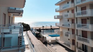 Un edificio alto con balcones que dan a una playa y una piscina.