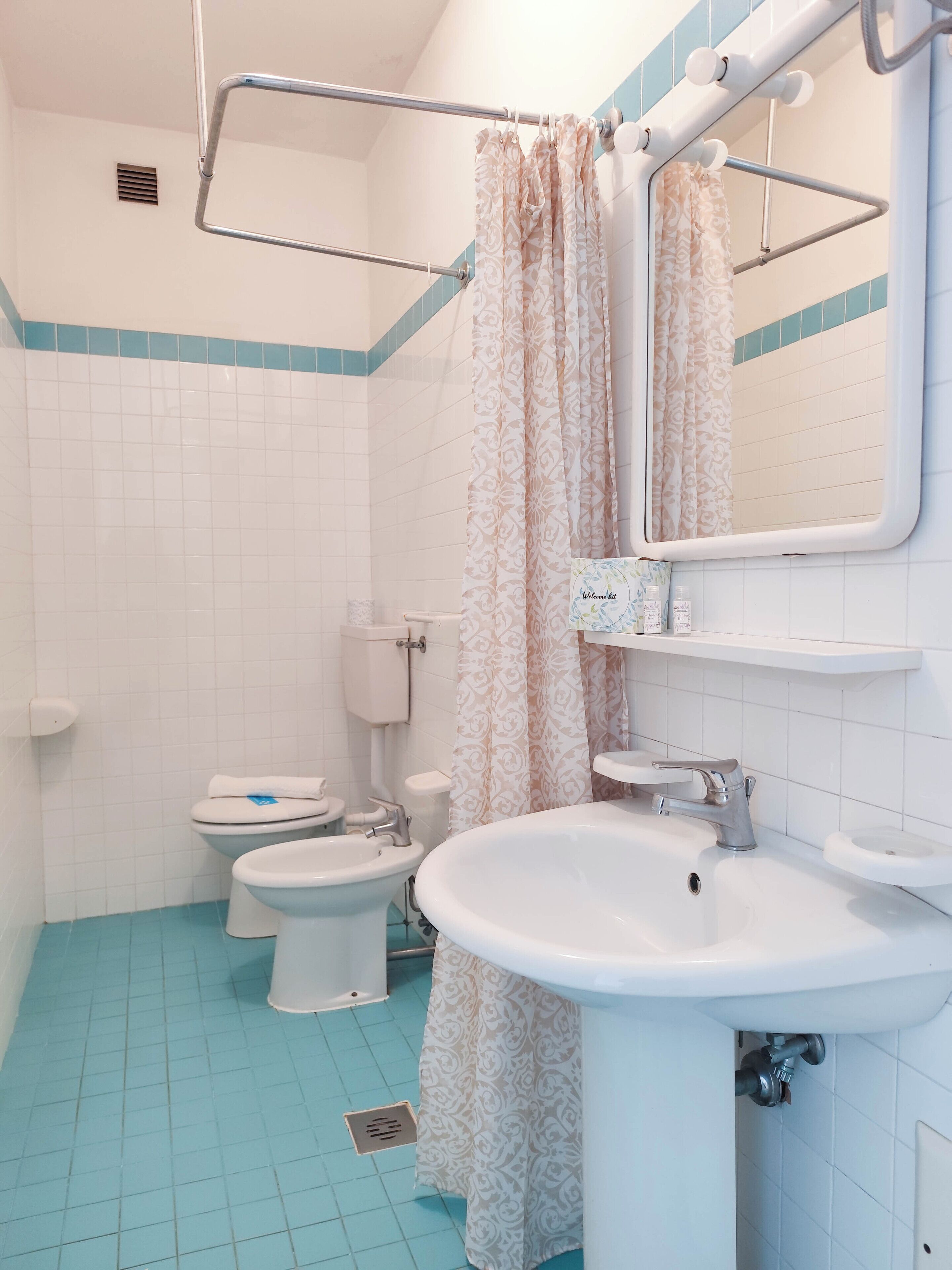 Une salle de bain équipée de toilettes, d’un bidet, d’un lavabo et d’un rideau de douche.