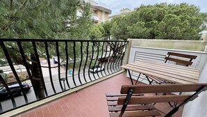 En balkon med træbænk og metalgelænder.