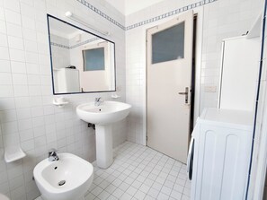 Un baño con lavabo, espejo, inodoro y puerta.