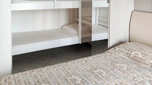 A bedroom with a bunk bed, a large mirror, and a floral bedspread. - Apartment with sea view balcony (Jesolo)