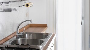 A kitchen with a gas stove, stainless steel sink, and wooden cabinets. - Apartment with sea view balcony (Jesolo)