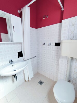 A bathroom with a white sink, a toilet, a shower area, and a mirror. - Comfortable flat near Jesolo beach (Lido di Jesolo)