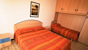 Ein Schlafzimmer mit Bett, Nachttisch, Kleiderschrank und einem gerahmten Bild an der Wand.