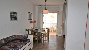 A compact living space with a sofa, dining table, chairs, and a balcony. - Studio with balcony and pool (Lido di Jesolo)