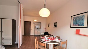 A compact hotel room with a dining area, kitchenette, and a bed. - Studio with balcony and pool (Lido di Jesolo)