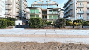 A modern apartment building with multiple balconies, a rooftop terrace, and a landscaped garden area. - Seafront apartment with private parking (Lido di Jesolo)