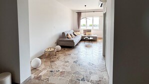 A modern living room with a grey sofa, a round coffee table, and a stone floor. - Seafront apartment with private parking (Lido di Jesolo)