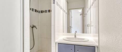 A bathroom with a shower, a sink, and a mirror.