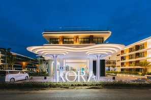 Et moderne hotel med en markant indgang og et stort, oplyst skilt.