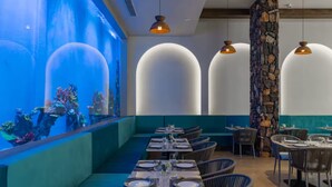 A restaurant with a long table, chairs, and a large aquarium wall.