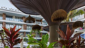 A multi-story hotel with a central atrium, large hanging lamps, and lush indoor plants.