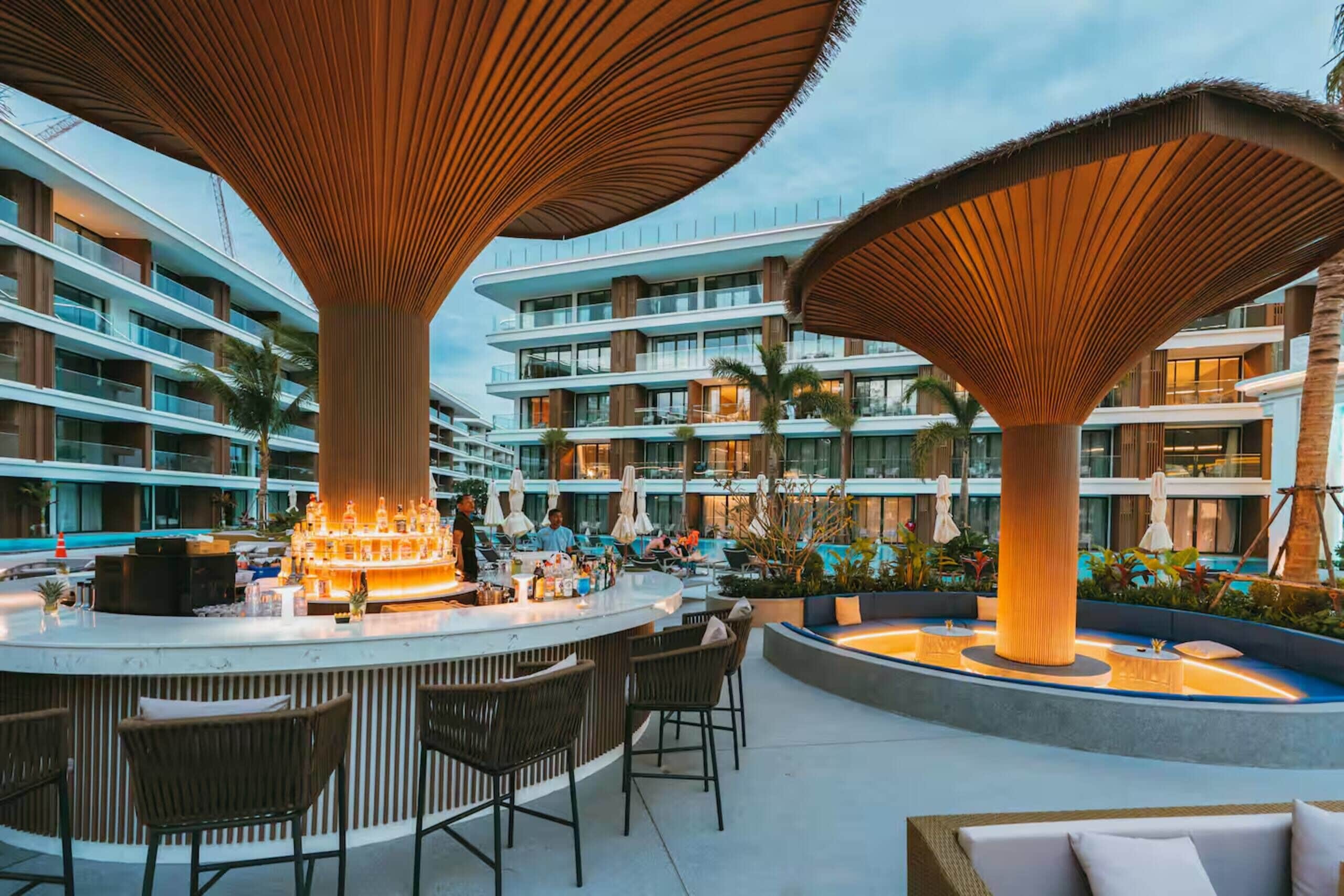 A modern hotel lobby with a bar area, outdoor seating, and a pool.