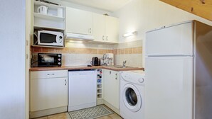 Eine kompakte Küche mit Mikrowelle, Kaffeemaschine, Geschirrspüler, Waschmaschine und Kühlschrank.
