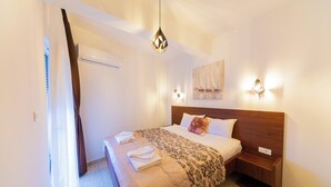 A hotel room with a bed, a nightstand, a wall-mounted lamp, and a painting. - Spacious 1BR Apt for 3 w/ Terrace & Pool (Sutomore)