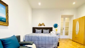 Une chambre à coucher comprenant un lit, un canapé, un miroir et une porte donnant sur une autre pièce.