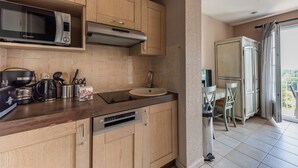 Uma cozinha moderna com armários de madeira, micro-ondas, cafeteira e máquina de lavar louça.
