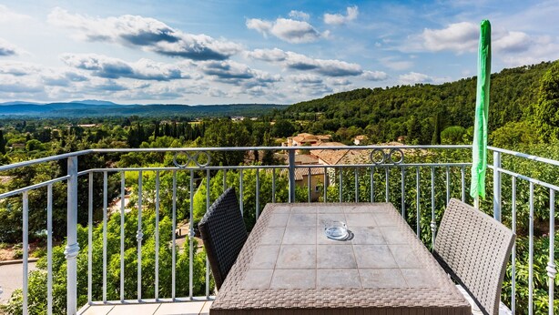Terraço com mesa e cadeiras, oferecendo vista de uma paisagem montanhosa.
