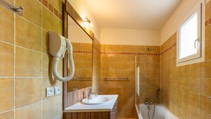 Un bagno con mobile contenitore in legno, lavabo, specchio, doccia e vasca da bagno.
