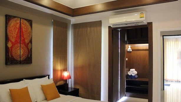 Een hotelkamer met een bed, een nachtkastje met een lamp, een wandairconditioner en een deur naar een badkamer.