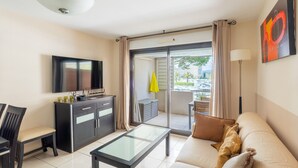 Un salon moderne avec un canapé, une table basse, un téléviseur et un balcon offrant une vue agréable.
